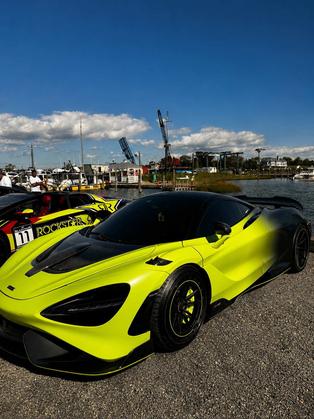 Neon yellow McLaren 765LT with carbon fiber accents at a waterfront marina