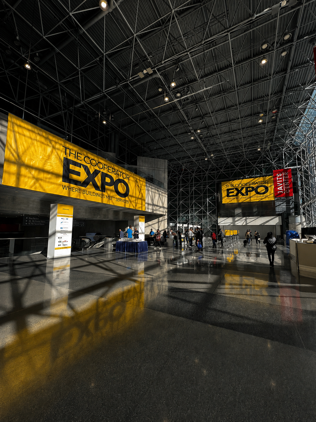 The Cooperator Expo entrance at the Javits Center with large yellow banners and attendees on the show floor
