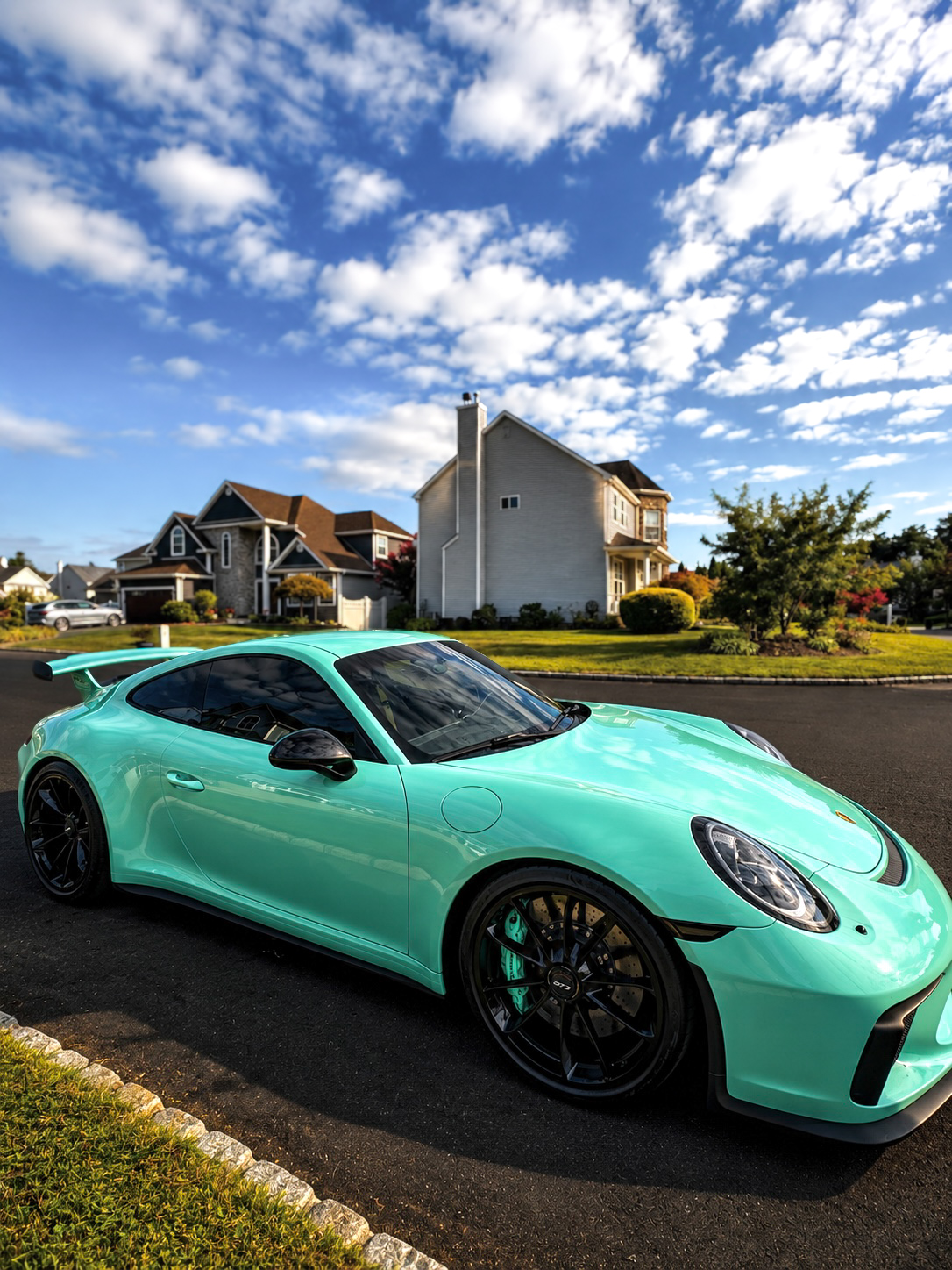 Mint green Porsche 911 GT3 parked in a suburban driveway at golden hour